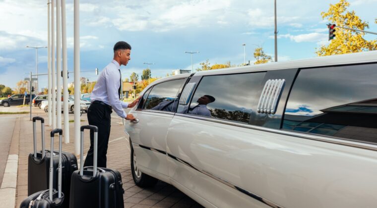 A man with luggage standing next to a white limo.