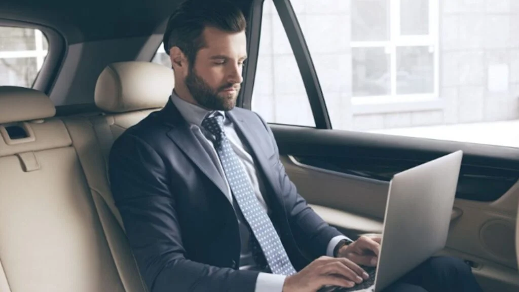 A man in a suit and tie sitting in the back of a car.