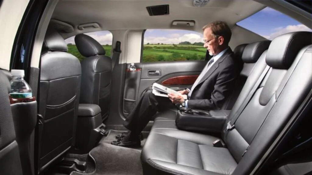 A man sitting in the back of a car reading.