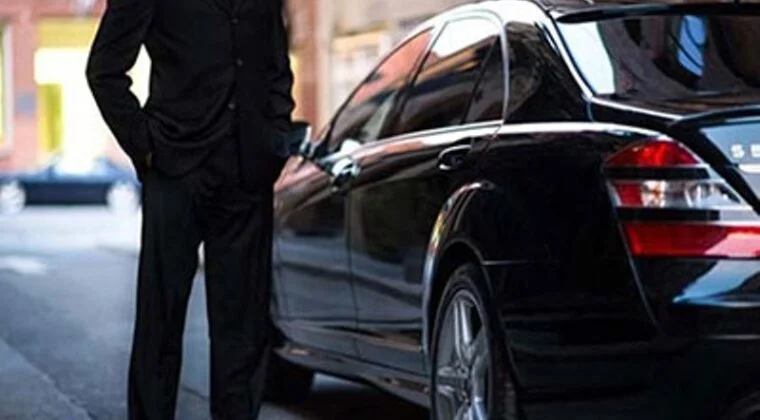 1-1-760x420 A man standing next to a black car.