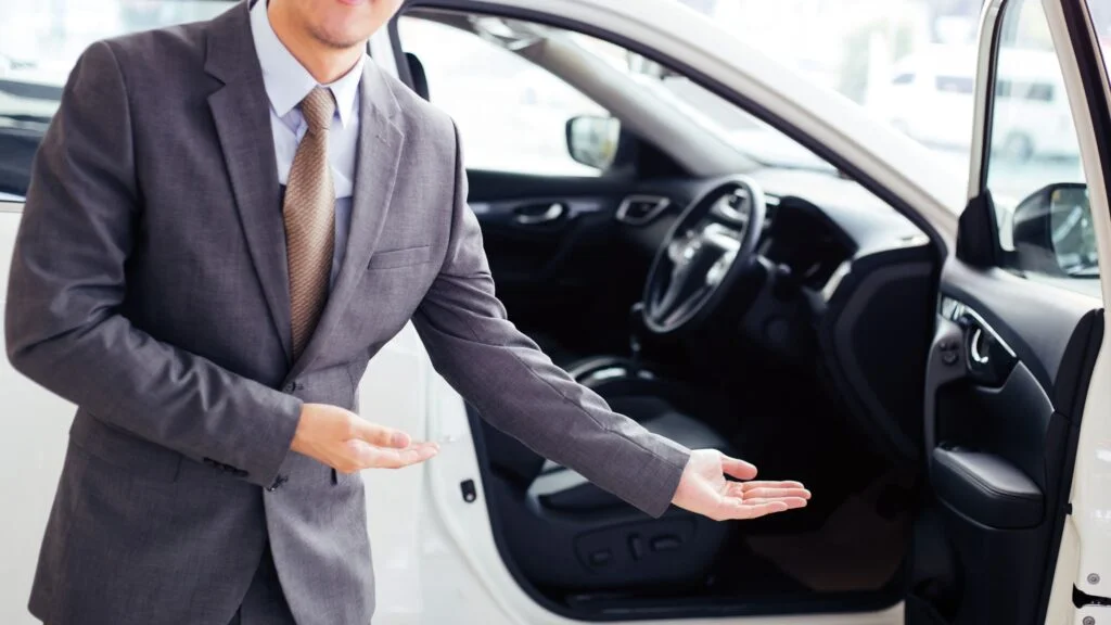 A man in a suit and tie standing next to a car.