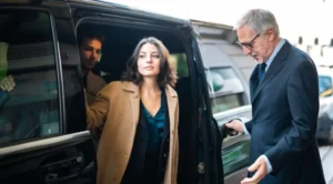 A woman in a brown coat is getting out of the car