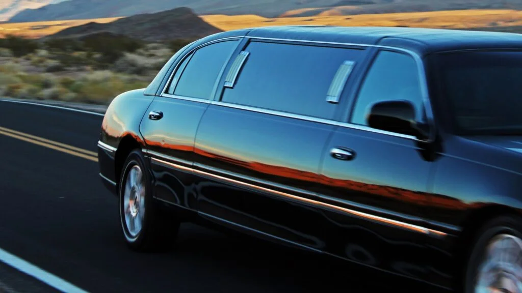 A limo driving down the road near some mountains.