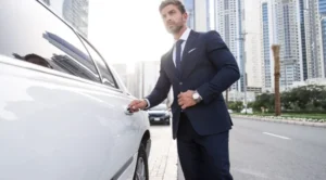 A man in a suit and tie standing next to a car.