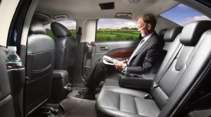 A man sitting in the back of a car reading.