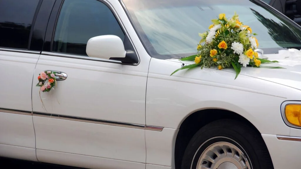 A white limo with flowers on the side.