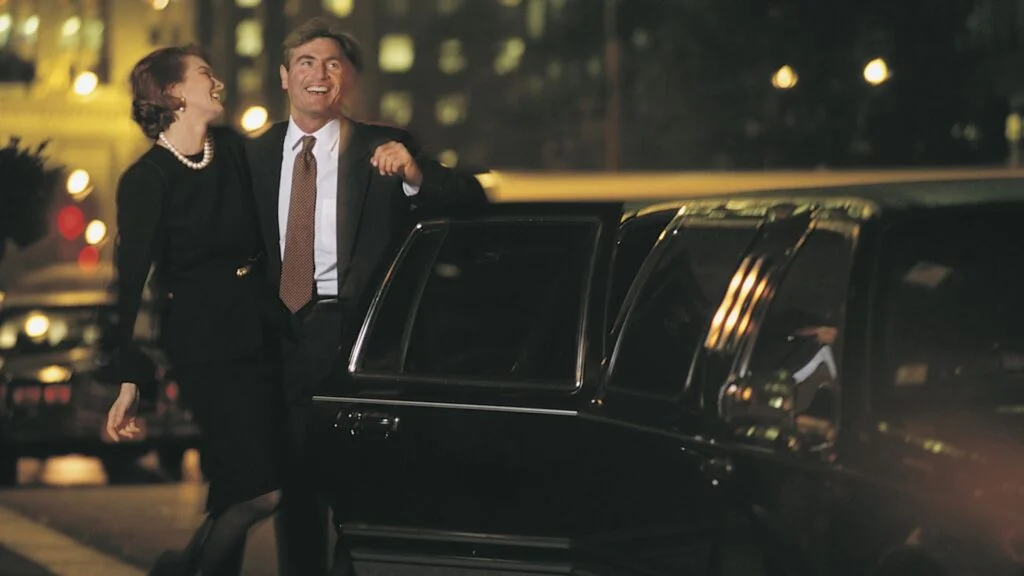 A man in a suit and tie standing next to a car.