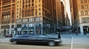 A limo driving down the street in front of tall buildings.