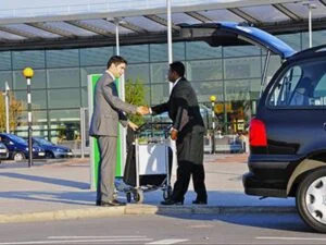 Two men shaking hands in front of a car.