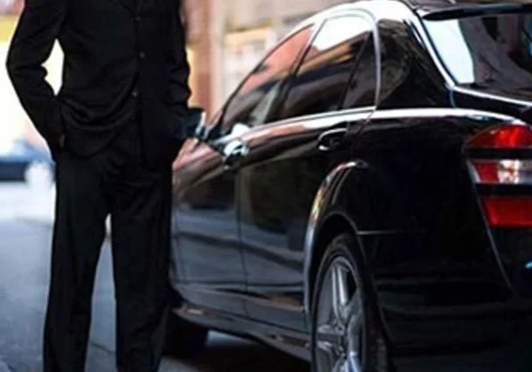 A man standing next to a black car.