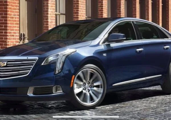 A blue cadillac is parked on the street.