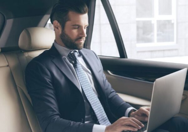 A man in a suit and tie sitting in the back of a car.