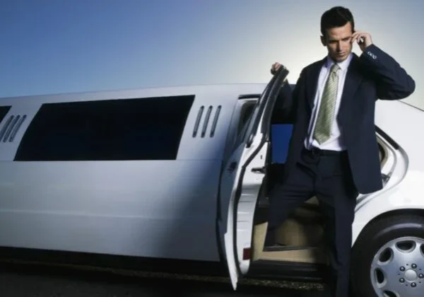 A man in suit and tie exiting a limo.