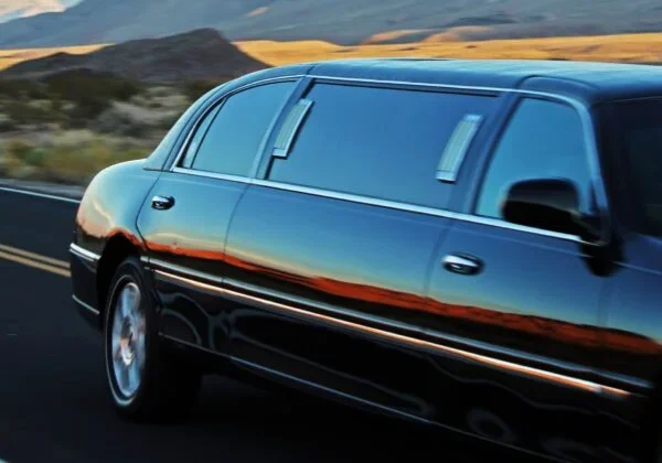 A limo driving down the road in front of mountains.