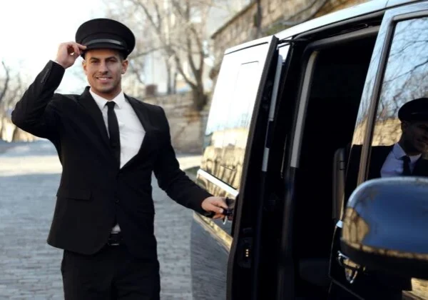 A man in black suit and hat standing next to a car.