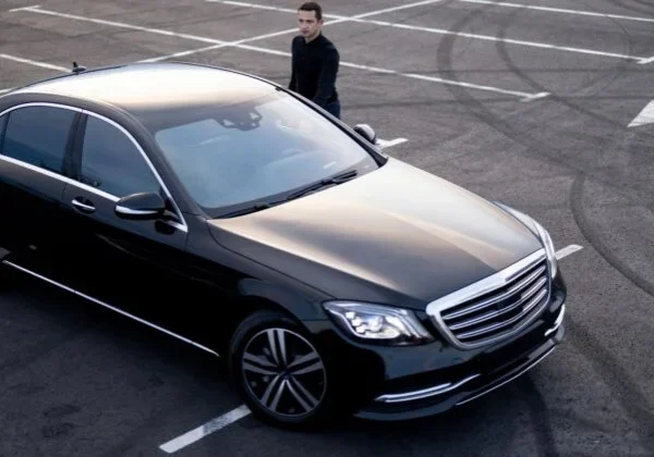 A man standing next to a black car.