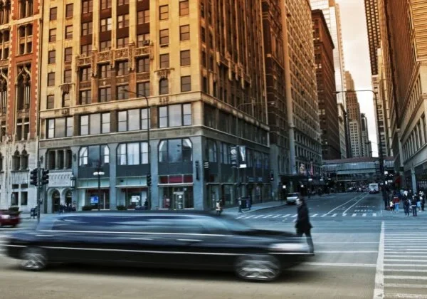 A limo driving down the street in front of tall buildings.