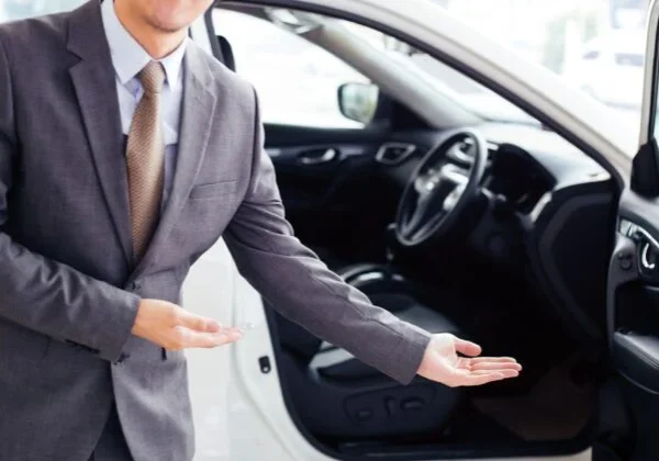 A man in a suit and tie standing next to a car.